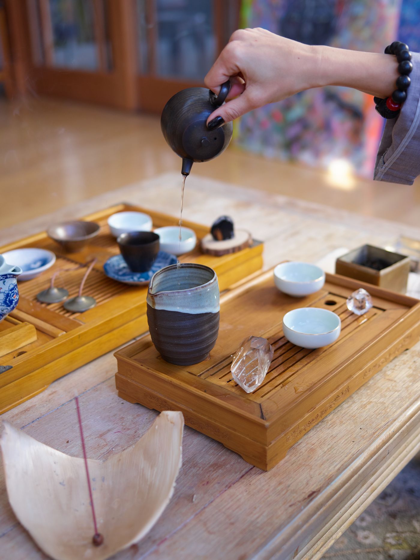 木质茶盘上正在分茶的陶壶与茶杯